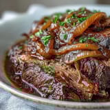 A close-up of Savory Crock Pot French Onion Pot Roast in a slow cooker, with bubbling juices and melted cheese topping.