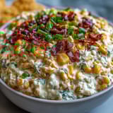 Golden baked Crack Corn Dip with creamy texture and green onions is scooped onto a blue plate with tortilla chips.
