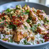 Creamy Thai-inspired peanut sauce drizzles generously over the colorful bowl, pooling around tender chicken and crunchy veggies for a rich, nutty finish.