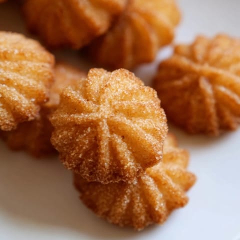 Golden-brown churro bites glistening with cinnamon sugar, perfect for a sweet dessert treat.