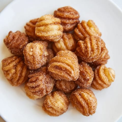 Freshly fried churro bites, warm and crispy, ready to be tossed in a sweet cinnamon coating.
