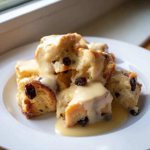 Delicious bread pudding served warm, drizzled with a creamy, rich vanilla sauce for satisfying flavors.