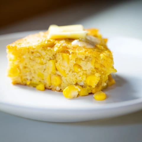 Golden, fluffy corn flapjacks, stacked high, drizzled with maple syrup—a delicious breakfast treat.