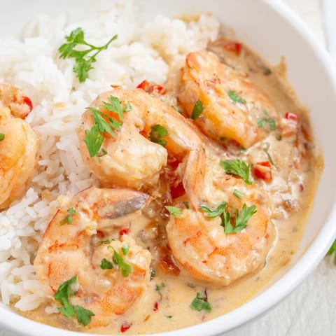 Tender Cajun shrimp in a rich, creamy sauce, served atop steaming jasmine rice for a comforting meal.