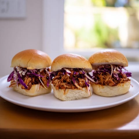 Savory BBQ chicken sliders piled with creamy coleslaw, ready to serve on a platter for game day.