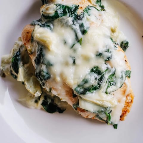 Tender baked chicken breasts topped with spinach, artichokes, and Greek yogurt, perfect for a comforting weeknight dinner.