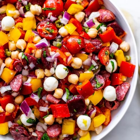 Overhead view of Crunchy Antipasto Chopped Salad featuring crisp cucumbers, peppers, and pepperoncini on a rustic table.