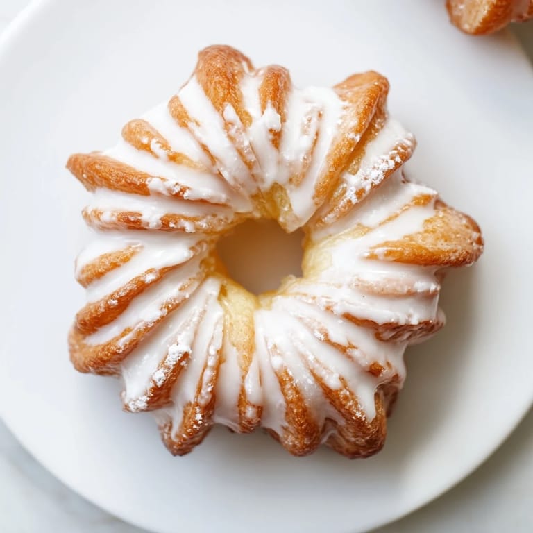 Freshly fried French crullers with a perfect swirl, ready to be enjoyed with a hot drink.