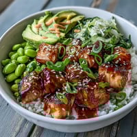 Golden baked salmon cubes and fluffy jasmine rice in a vibrant Salmon Rice Bowl with edamame and sliced avocado.